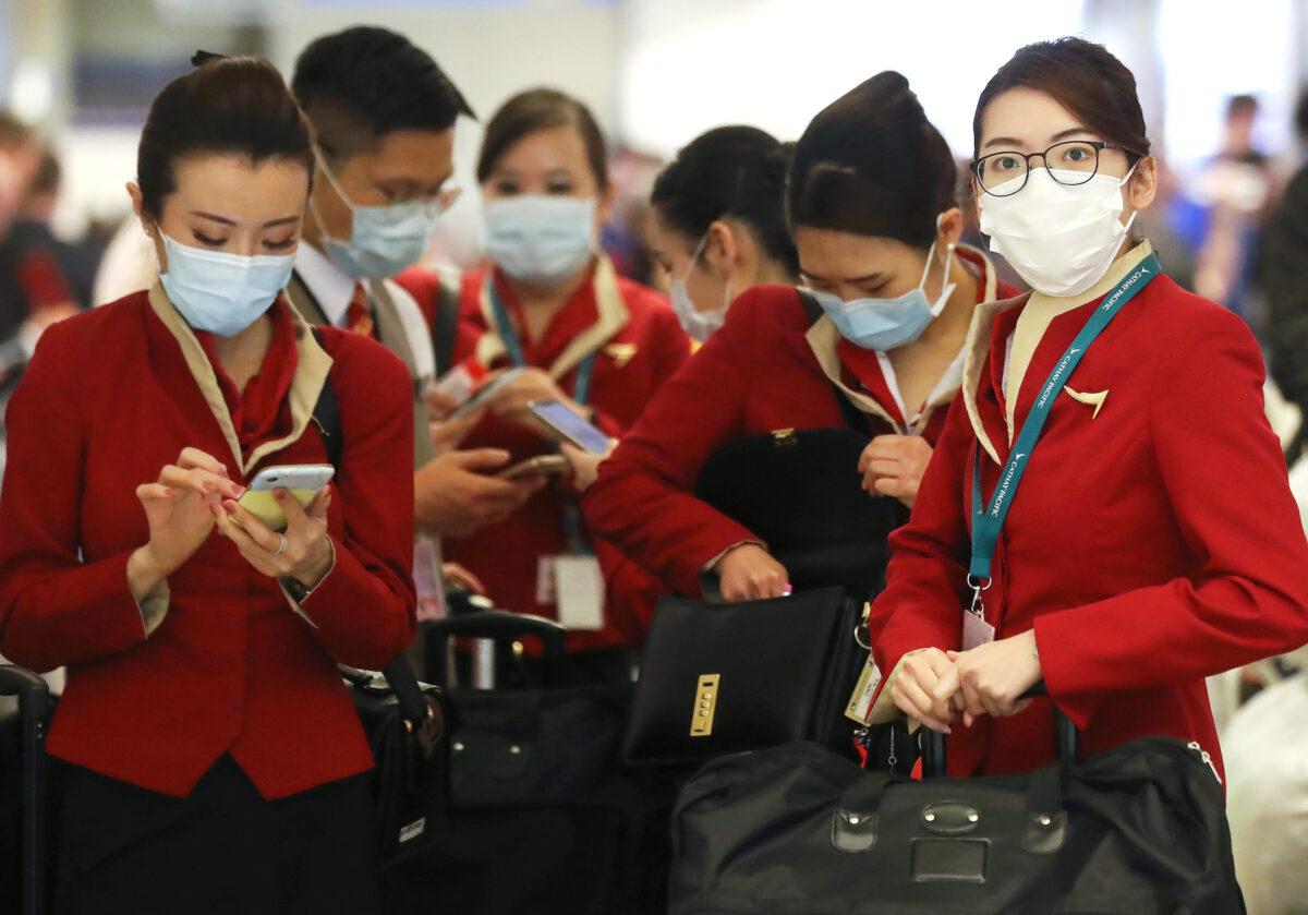 A flight crew from Cathay Pacific Airways, wearing protective masks, stands in the international terminal after arriving on a flight from Hong Kong at Los Angeles International Airport in Los Angeles, Calif., on Feb. 28, 2020. (Mario Tama/Getty Images)
