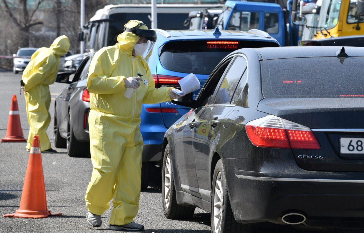 Medical workers wearing protective gear guide drivers with suspected symptoms of the COVID-19 coronavirus at a "drive-through" virus test facility in Goyang, north of Seoul, on Feb. 29, 2020. (Jung Yeon-Je/AFP via Getty Images)