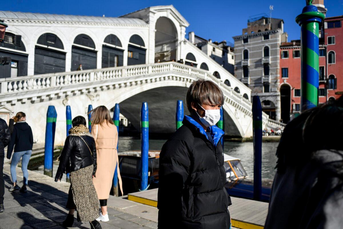 A man wearing a protective mask walks past the Ponte di Rialto (Rialto Bridge) in Venice, Italy on Feb. 28, 2020. (Claudio Furlan/Lapresse via AP)
