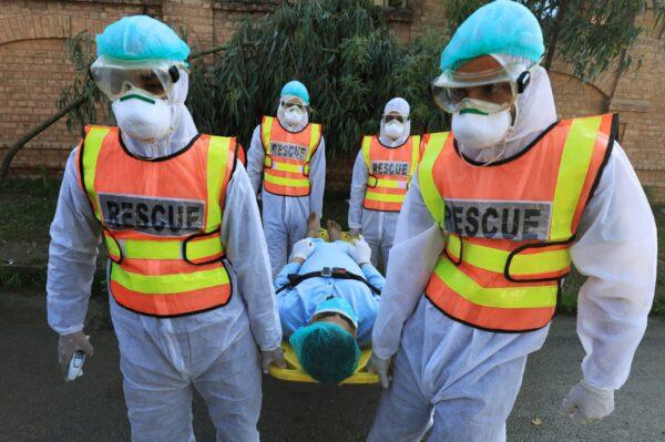 Rescue workers wearing masks and protective clothing move a man during a mock drill on handling suspected carriers of coronavirus, in Peshawar, Pakistan, on March 2, 2020. (Fayaz Aziz/Reuters)