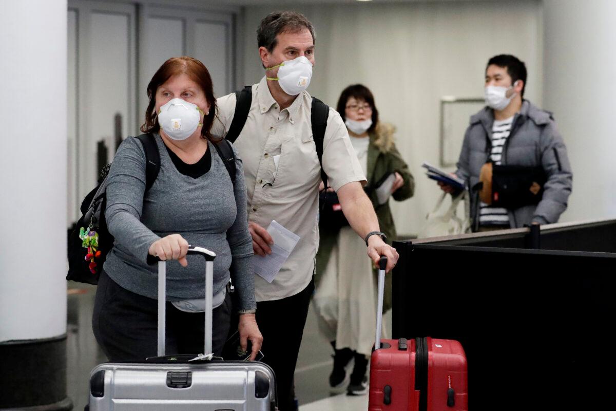Travelers wear protective mask as they walk through in terminal 5 at O'Hare International Airport in Chicago on March 1, 2020. (Nam Y. Huh/AP Photo)