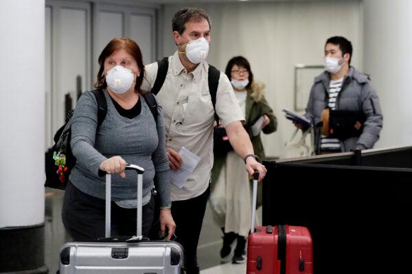 Travelers wear protective masks as they walk through terminal 5 at O'Hare International Airport in Chicago on March 1, 2020. (Nam Y. Huh/AP Photo)