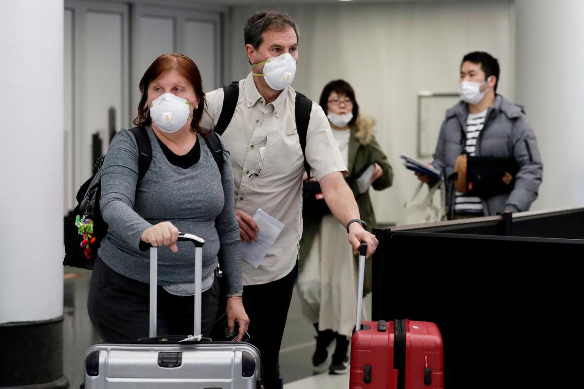 Travelers wear protective mask as they walk through in terminal 5 at O'Hare International Airport in Chicago, Illinois, on March 1, 2020. (Nam Y. Huh/AP Photo)