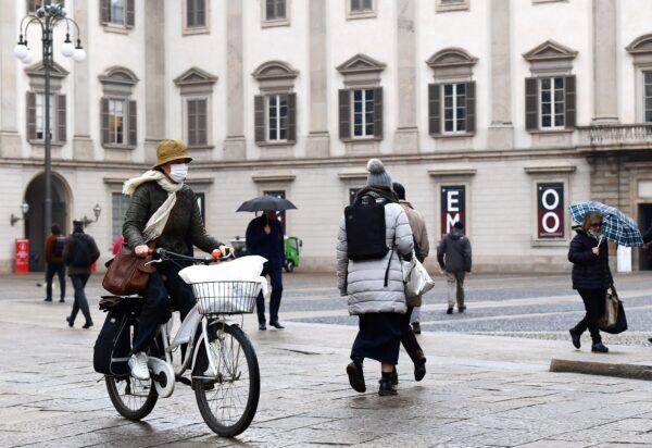 A woman wearing a protective mask crosses Piazza Duomo with her bicycle in Milan on March 2, 2020. (Miguel Medina/AFP via Getty Images)