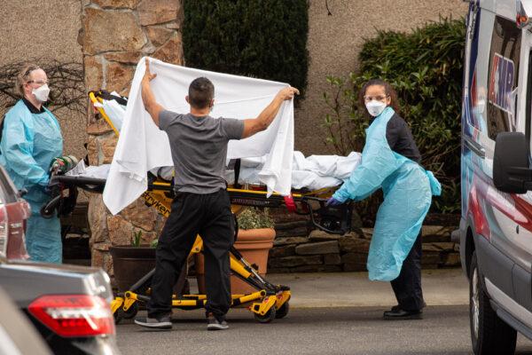 A worker shields a patient on a stretcher being taken to an ambulance at the Life Care Center of Kirkland in Washington state on Feb. 29, 2020. (David Ryder/Getty Images)