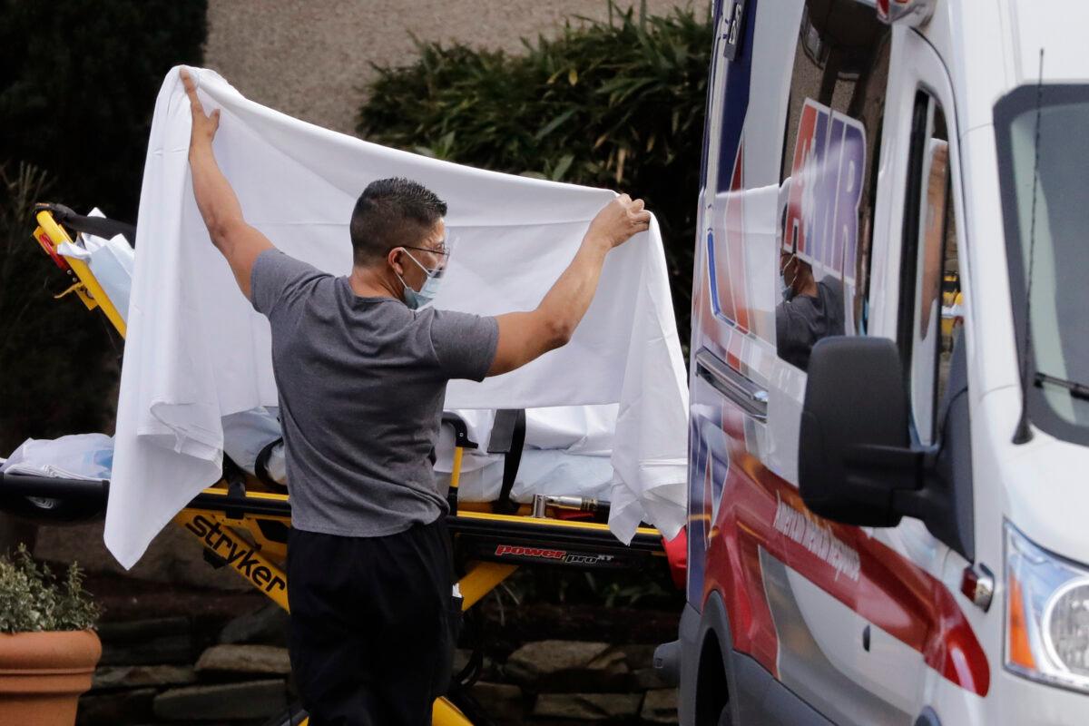 A man blocks the view as a person is taken by a stretcher to a waiting ambulance from a nursing facility where more than 50 people are sick and being tested for the COVID-19 virus in Kirkland, Wash., on Feb. 29, 2020. (Elaine Thompson/AP Photo)