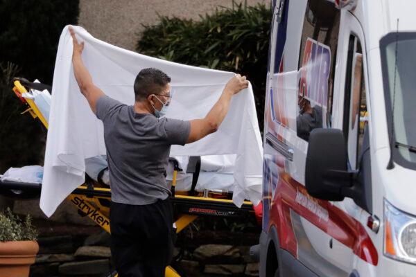 A man blocks the view as a person is taken by a stretcher to a waiting ambulance from a nursing facility where more than 50 people are sick and being tested for COVID-19 in Kirkland, Washington, on Feb. 29, 2020. (Elaine Thompson/AP Photo)
