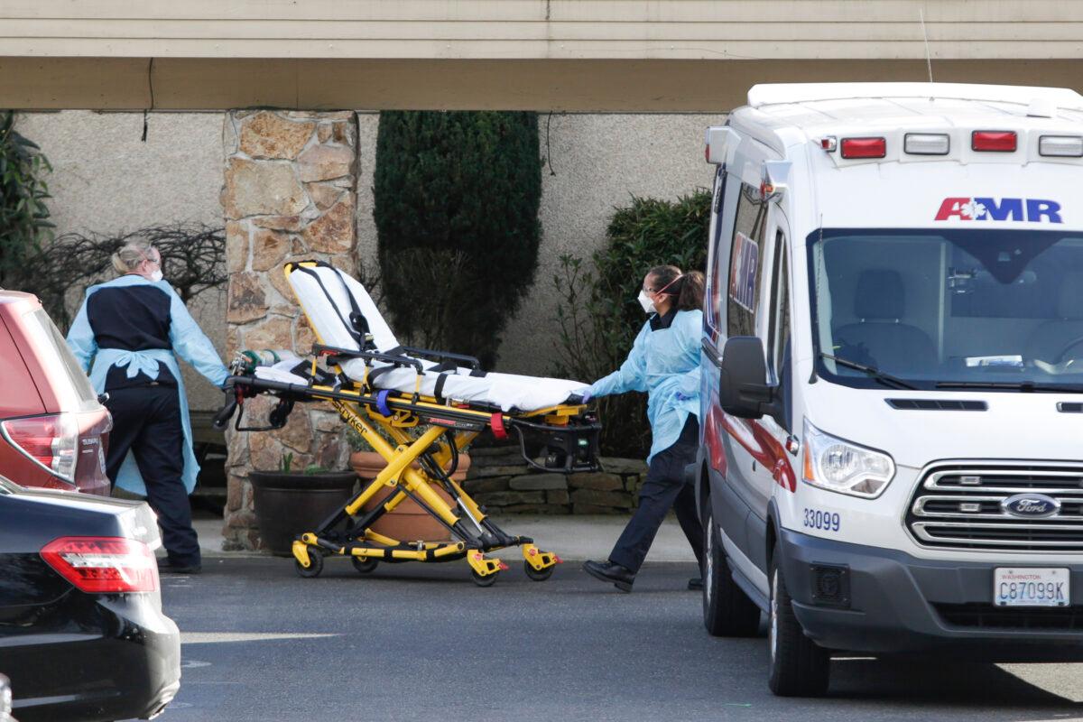 A stretcher is moved from an AMR ambulance to the Life Care Center of Kirkland where one associate and one resident were diagnosed with the CCP virus on Feb. 29, 2020. (Jason Redmond/AFP via Getty Images)