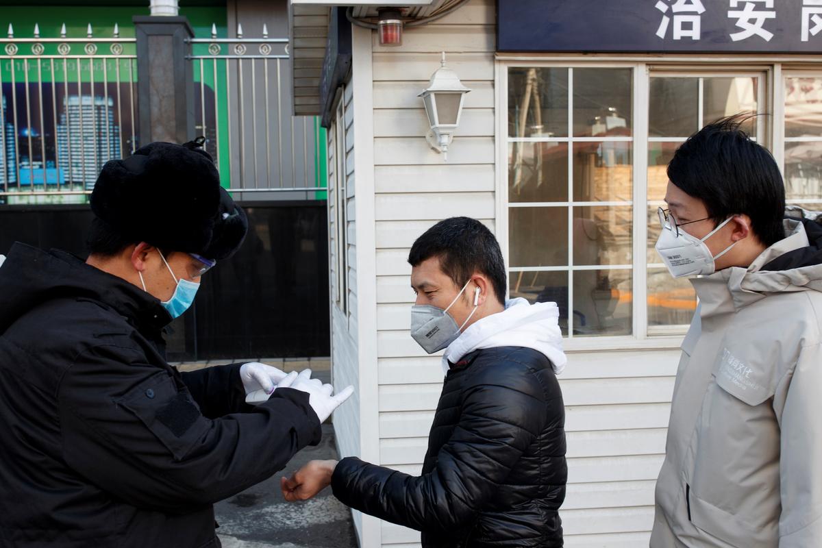 A security guard takes the temperature of people as they arrive for work at an office building in Beijing, as the country is hit by an outbreak of the novel coronavirus, on March 3, 2020. (Thomas Peter/Reuters)
