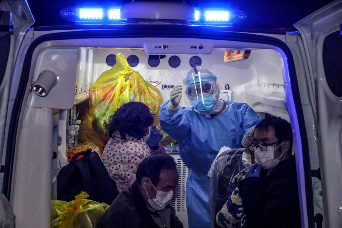 A medical staff member (C) gestures on an ambulance as patients infected by the COVID-19 coronavirus leave from Wuhan No.5 Hospital to Leishenshan Hospital, the newly-built hospital in Wuhan, China, on March 3, 2020. (STR/AFP via Getty Images)