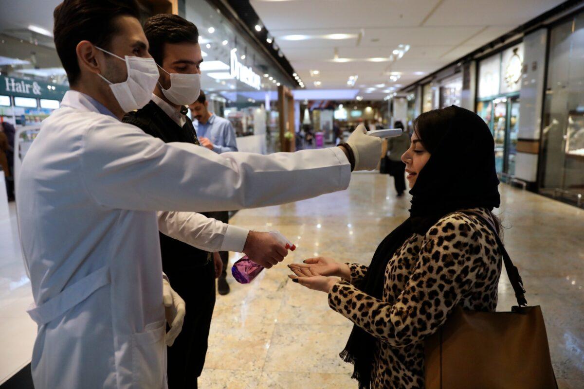 A woman has her temperature checked and her hands disinfected as she enters the Palladium Shopping Center, in northern Tehran, Iran, on March 3, 2020. (Vahid Salemi/AP Photo)