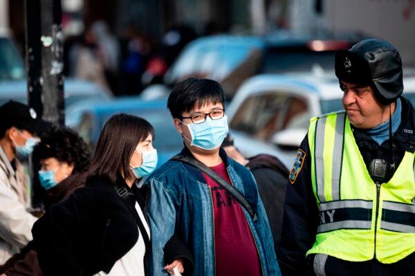 People wear face masks as they pass a traffic policeman in the Flushing area of Queens in New York City on March 2, 2020. (Johannes Eisele/AFP via Getty Images)