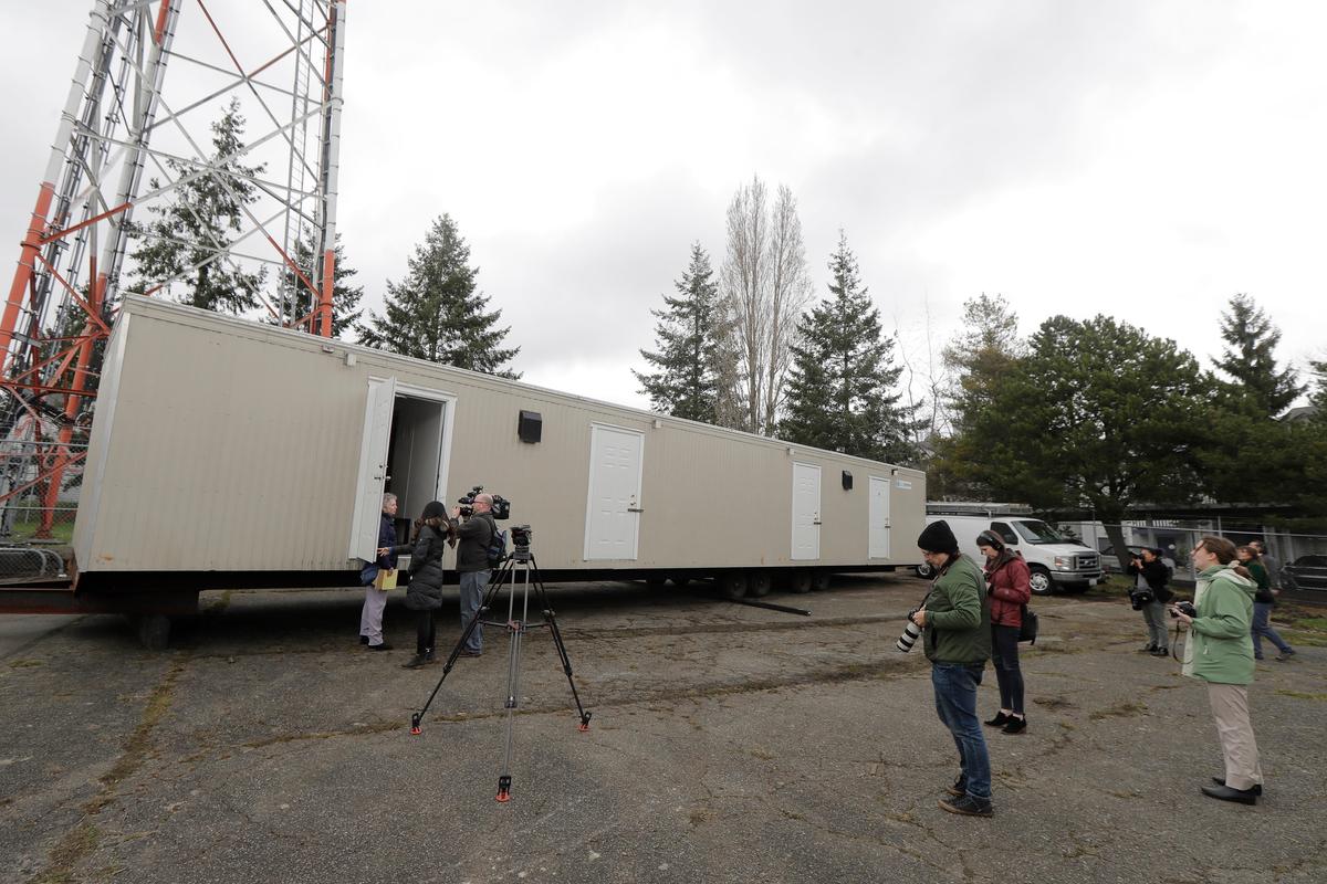 Reporters and photographers work at the site in South Seattle where King County will be placing several temporary housing units like the one shown here to house patients undergoing treatment and isolation in response to the COVID-19 coronavirus on March 3, 2020. (Ted S. Warren/AP Photo)