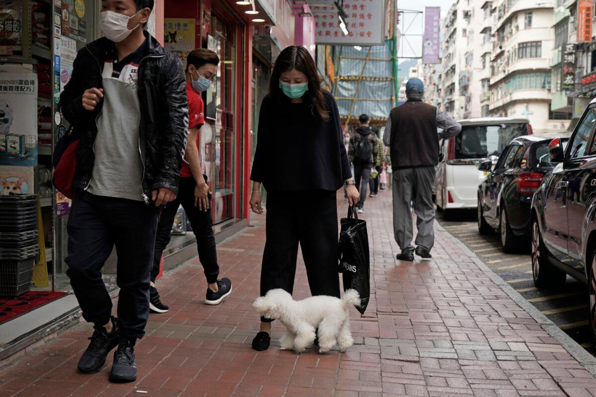 A woman wearing a face mask and a dog walk on street in Hong Kong, in Hong Kong on March 5, 2020. (Kin Cheung/AP Photo)