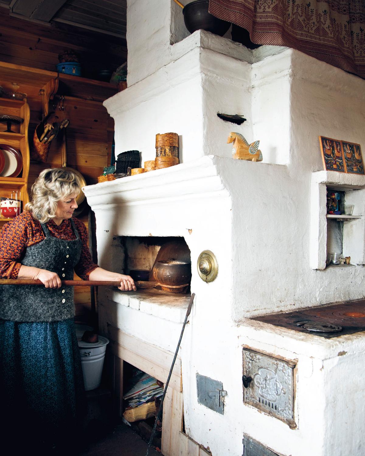 A woman tends to a traditional Russian masonry stove, the heart of Russian cooking. (Stefan Wettainen)