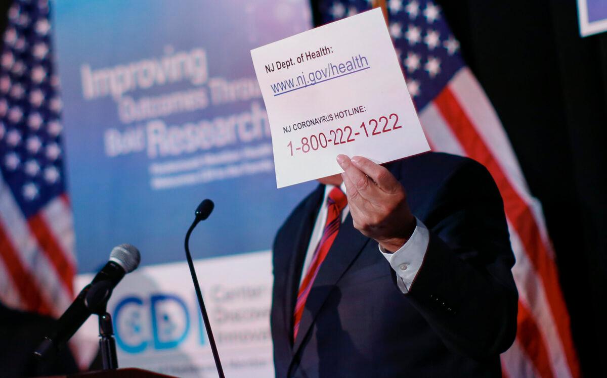 Sen. Bob Menendez (D-N.J.) holds up a sign that lists the state's coronavirus hotline at a press conference in Nutley, New Jersey on Feb. 28, 2020. (Kena Betancur/Getty Images)