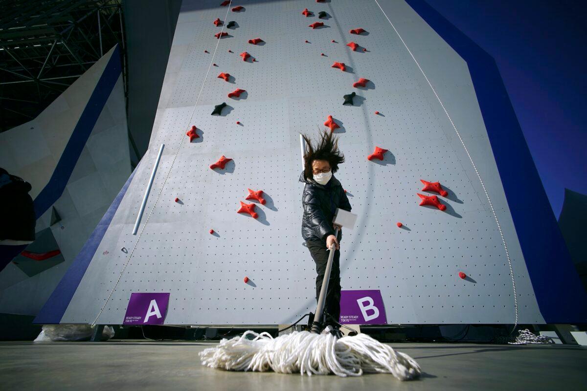 A staff member mops the floor in front of the climbing wall in the test event of Speed Climbing in preparation for the Tokyo 2020 Olympic Games at Aomi Urban Sports Park in Japan on March 6, 2020. (Eugene Hoshiko/AP Photo)