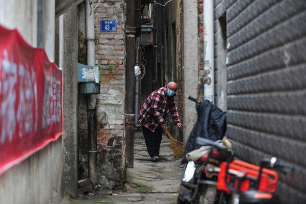 A resident wearing a face mask sweeps the floor in Wuhan in China's central Hubei province on March 4, 2020. (STR/AFP via Getty Images)