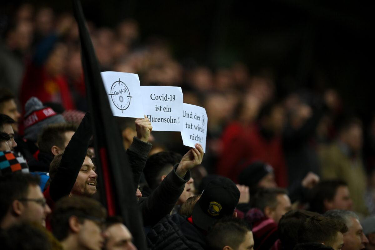 Fans hold signs with messages regarding the new coronavirus during a game at BayArena in Leverkusen, Germany, on March 4, 2020. (Matthias Hangst/Bongarts/Getty Images)