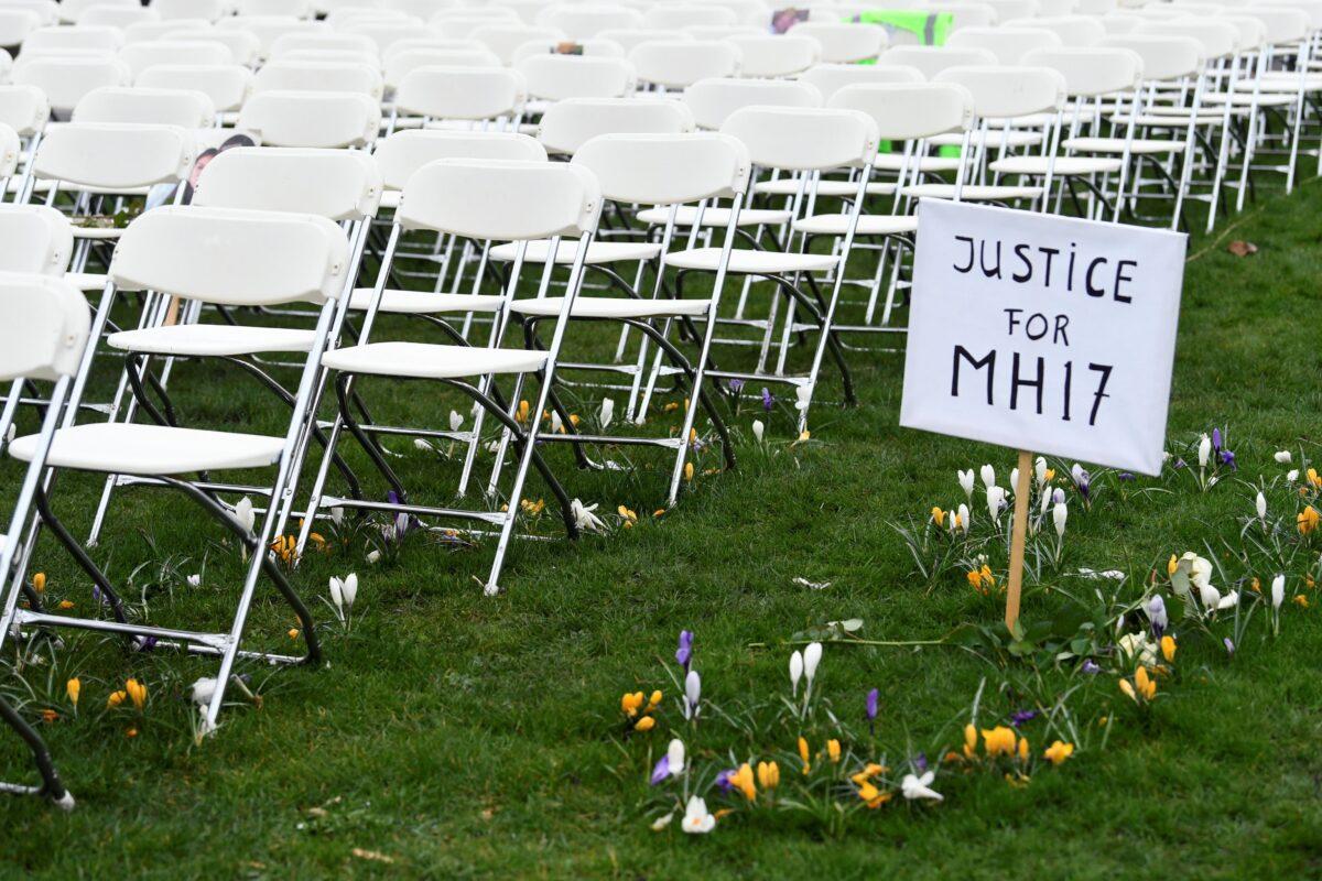 A protest sign stands next to rows of empty chairs, lined up by family members of victims of the MH17 crash, during a protest outside the Russian Embassy in The Hague, Netherlands, on March 8, 2020. (Piroschka van de Wouw/Reuters)