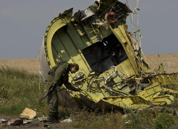 A pro-Russian rebel touches the MH17 wreckage at the crash site of Malaysia Airlines Flight 17, near the village of Hrabove, eastern Ukraine, on July 22, 2014. (Vadim Ghirda/File via AP)