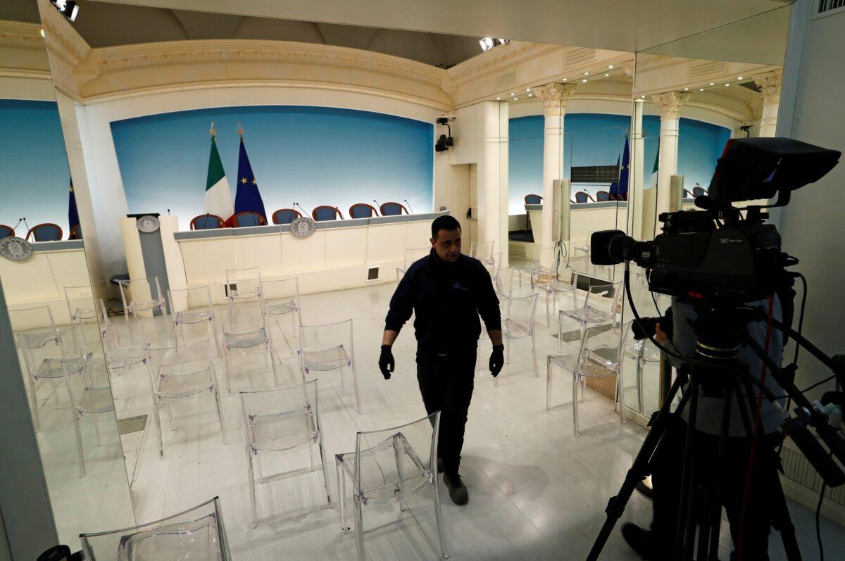 Workers in the Italian Prime Minister’s office of Palazzo Chigi remove chairs in the news briefing room in order to adhere to restrictions that people are one meter apart, due to coronavirus spread, in Rome, Italy, on March 9, 2020. (Remo Casilli/Reuters)