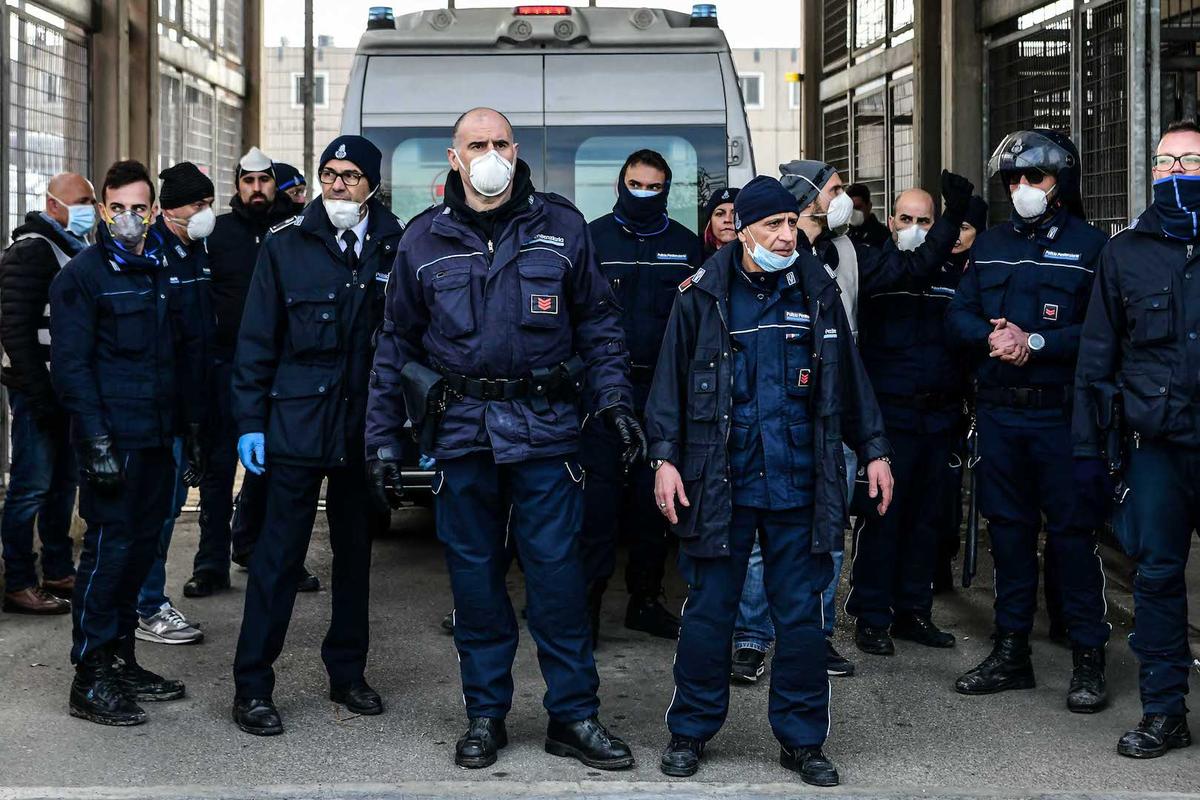 Prison police officers stand guard after an ambulance entered the SantAnna prison during a protest of inmates' relatives in Modena, Emilia-Romagna, in one of Italy's quarantine red zones on March 9, 2020. (Piero Cruciatti/AFP via Getty Images)