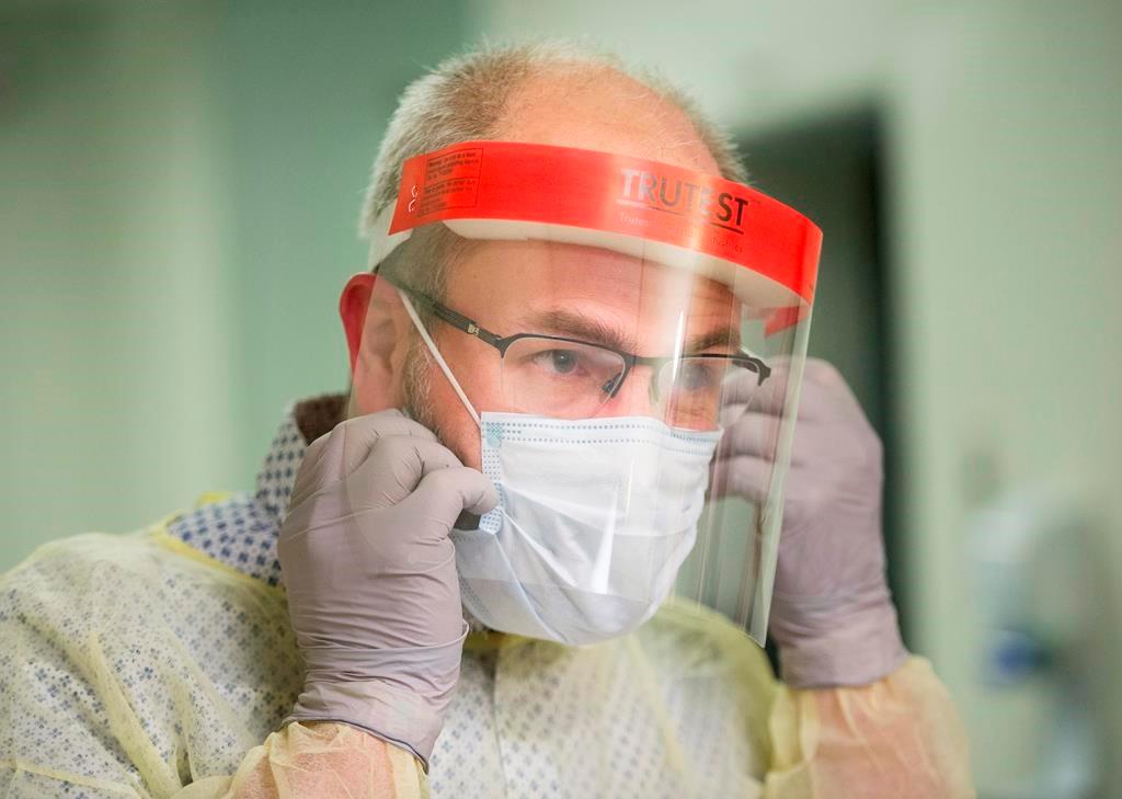A man demonstrates how to put on a mask and other protective clothing during a tour of a COVID-19 evaluation clinic in Montreal, on March 10, 2020. (Graham Hughes/The Canadian Press)