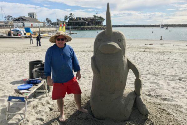 Chris Crosson, defending champion in the Whale of a Sand sculpting competition, stands with his narwal on March 7, 2020. (Chris Karr/The Epoch Times)
