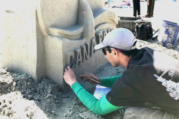 JT Estrela carves the Dana Point Festival of Whales logo in sand at the kick-off of the week-long festival, on March 7, 2020. (Chris Karr/The Epoch Times)