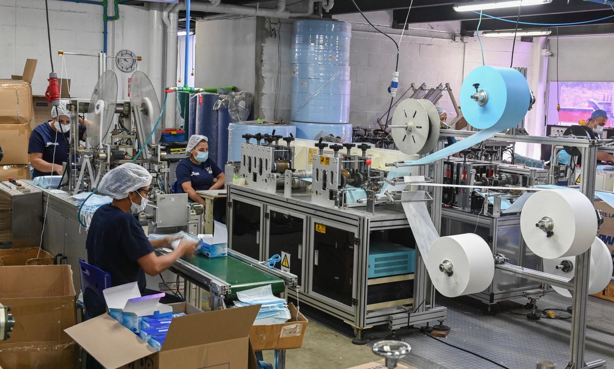 Women work in the assembly line of protective face masks at the JMM health supplies company, in Sabaneta, near Medellin, Colombia, on March 9, 2020. (JOAQUIN SARMIENTO/AFP via Getty Images)