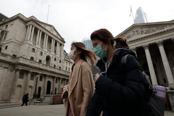 Pedestrians wearing protective masks walk past the Bank of England in London on March 11, 2020. (Matt Dunham/AP Photo)