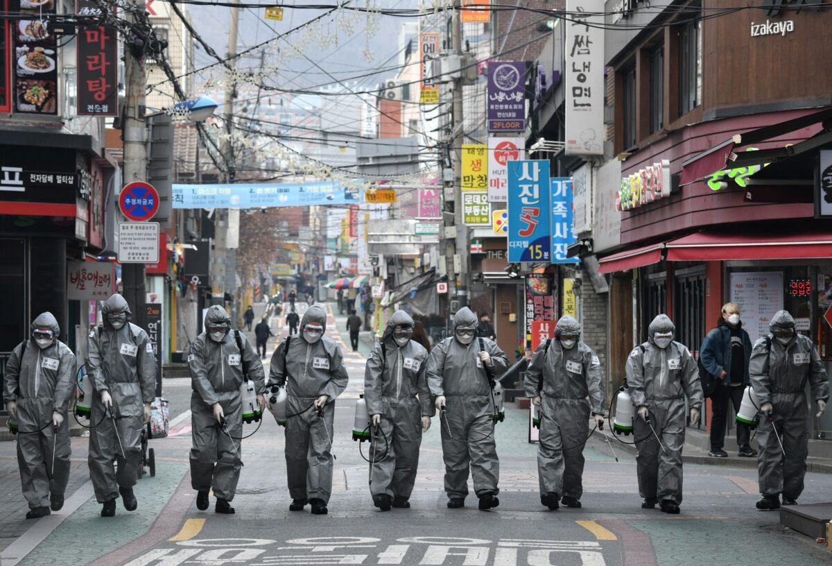 South Korean soldiers wearing protective gear spray disinfectant to help prevent the spread of COVID-19, at a shopping district in Seoul on March 4, 2020. (Jung Yeon-je/AFP via Getty Images)