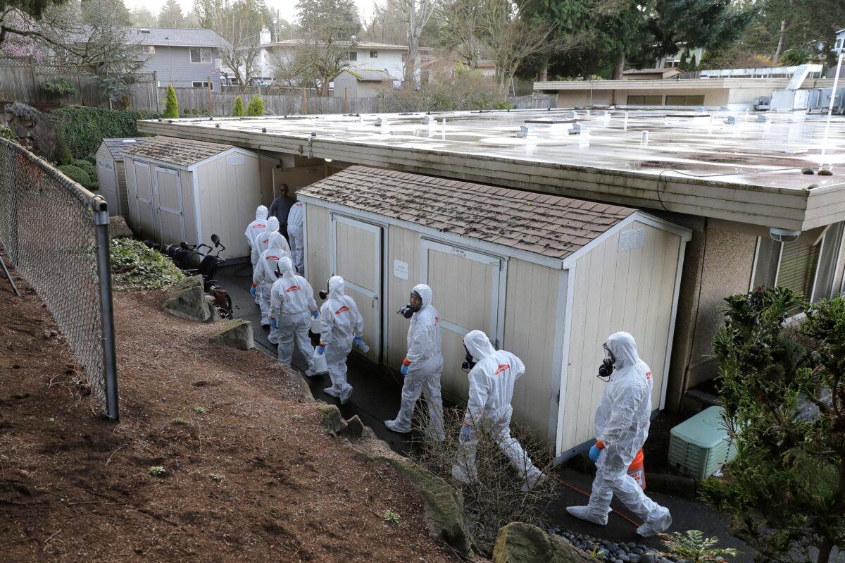 Workers from a Servpro disaster recovery team wearing protective suits and respirators enter the Life Care Center in Kirkland, Wash., to begin cleaning and disinfecting the facility on March 11, 2020, near Seattle. The nursing home is at the center of the coronavirus outbreak in Washington state. (Ted S. Warren/AP Photo)