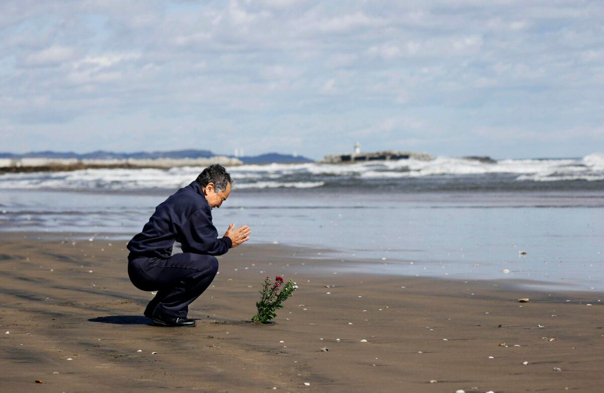 A man offers a prayer for the victims of the 2011 earthquake and tsunami, on the coastal area in Iwaki, northern Japan, Wednesday, March 11, 2020. (Naoya Osato/Kyodo News via AP)