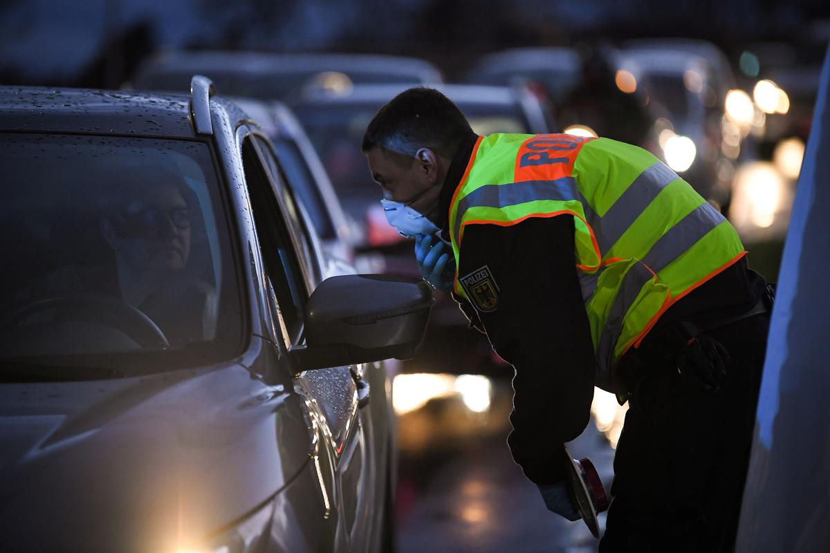 A German police officer wearing a protective mask speaks to a driver at the French and German border between the cities of Strasbourg and Kehl as part of measures taken due to the COVID-19 outbreak in Europe on March 12, 2020. (Patrick Hertzog/AFP via Getty Images)