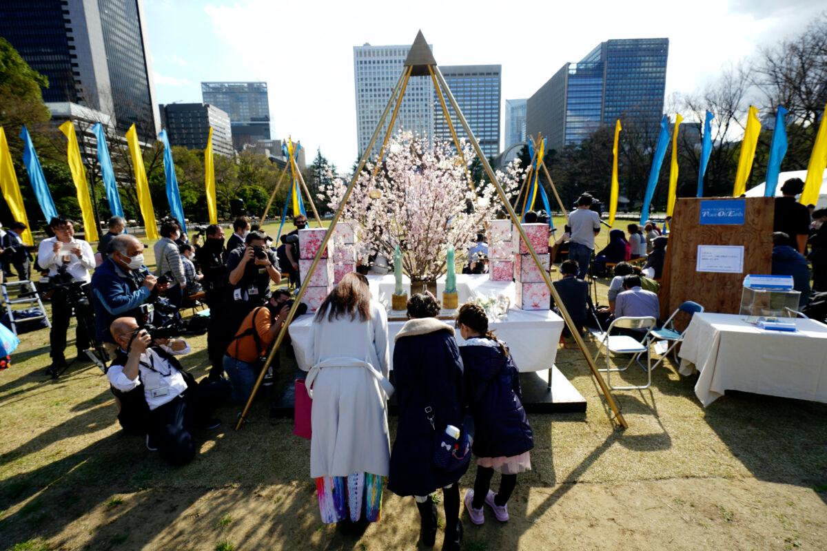 Visitors pray at a makeshift altar to mourn for victims of the March 11, 2011, earthquake and tsunami during a special memorial event in Tokyo Wednesday, March 11, 2020. (AP Photo/Eugene Hoshiko)