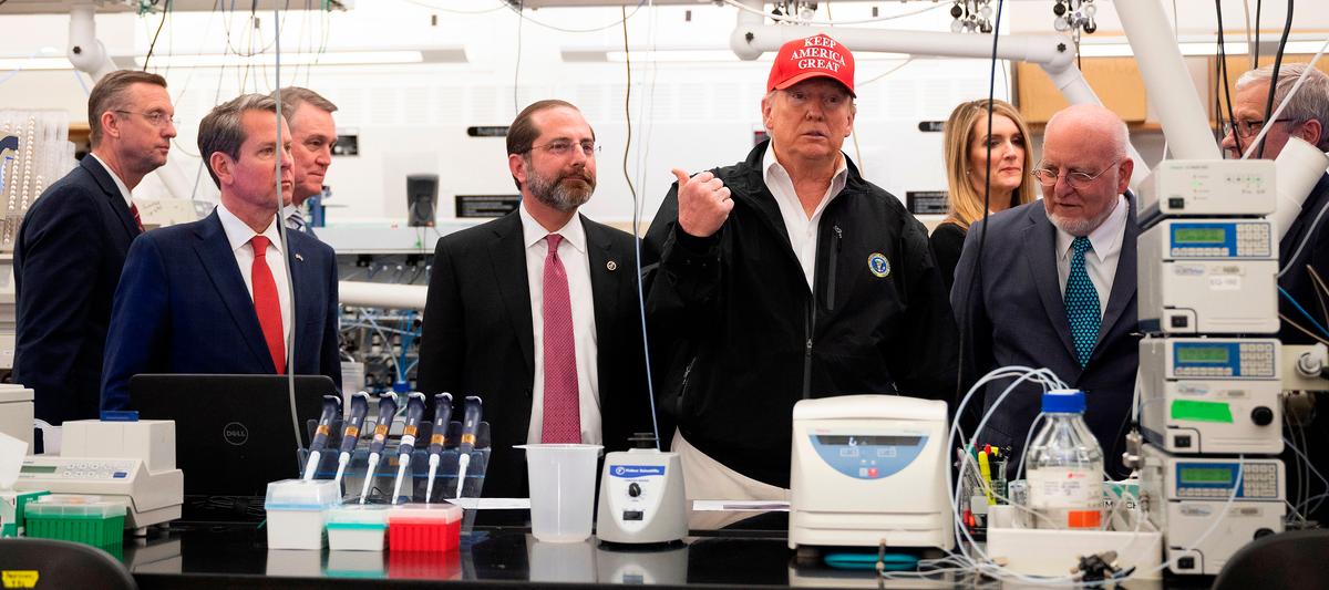President Donald Trump, center, gestures alongside Health and Human Service Secretary Alex Azar, second from left, CDC Director Robert Redfield, second from right, and CDC Associate Director for Laboratory Science and Safety Dr. Steve Monroe, right, Sen. Kelly Loeffler (R-Ga.), third from right, Georgia Gov. Brian Kemp, second from left, and Rep. Doug Collins (R-Ga.), left, during a tour of the Centers for Disease Control and Prevention in Atlanta, Georgia, on March 6, 2020. (Jim Watson/AFP via Getty Images)