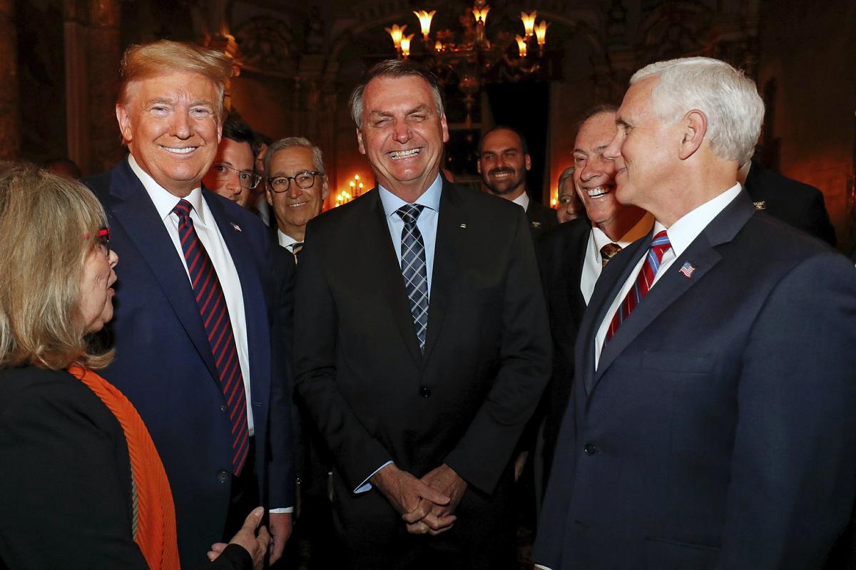 Brazil's President Jair Bolsonaro, center, stands with President Donald Trump, second from left, Vice President Mike Pence, right, and Brazil's Communications Director Fabio Wajngarten, behind Trump partially covered, during a dinner in Florida on March 7, 2020. (Alan Santos/Brazil's Presidential Press Office via AP)