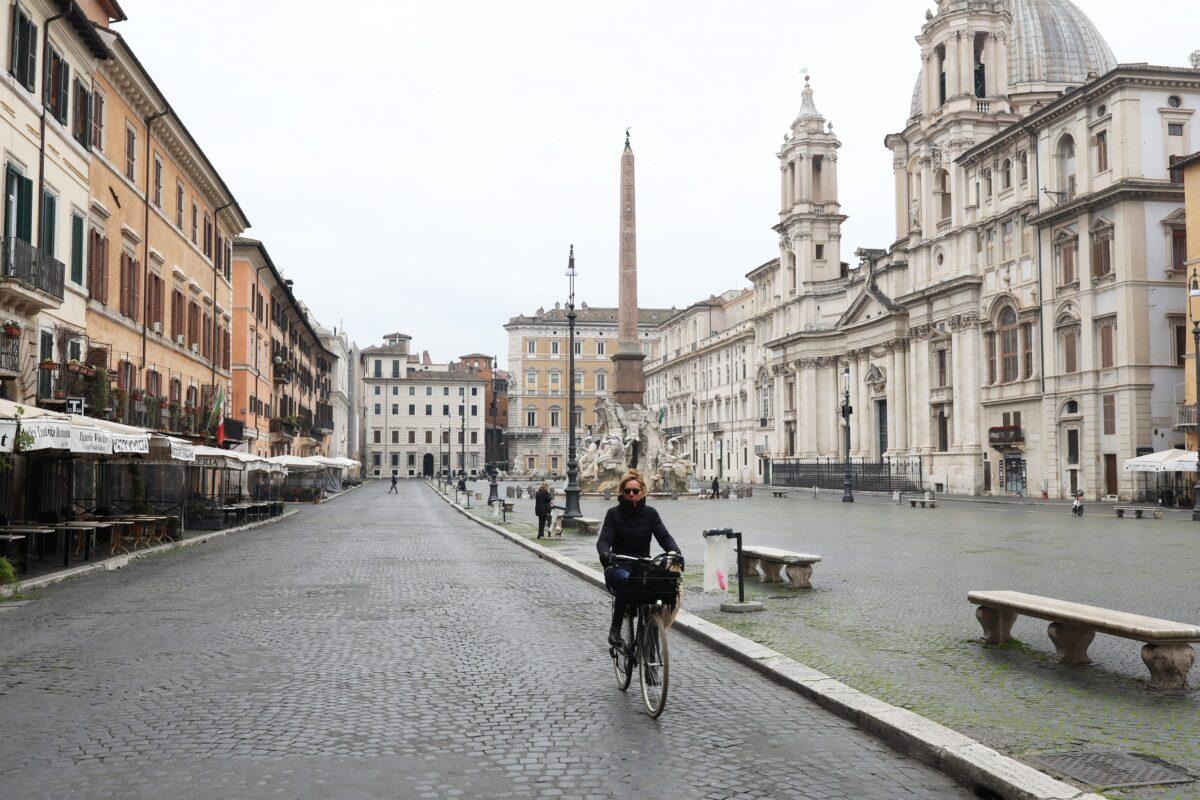 A woman is seen cycling in a completely empty Navona Square in Rome, Italy, on March 13, 2020. Rome's streets were eerily quiet on the second day of a nationwide shuttering of schools, shops and other public places. (Marco Di Lauro/Getty Images)