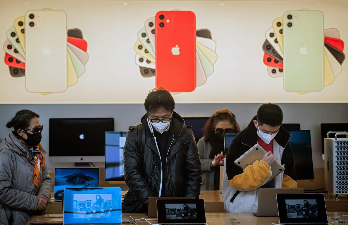 Customers wearing masks as a preventive measure against the COVID-19 coronavirus are seen inside of an Apple shop in Beijing, China. (Nicolas Asfouri/AFP via Getty Images)