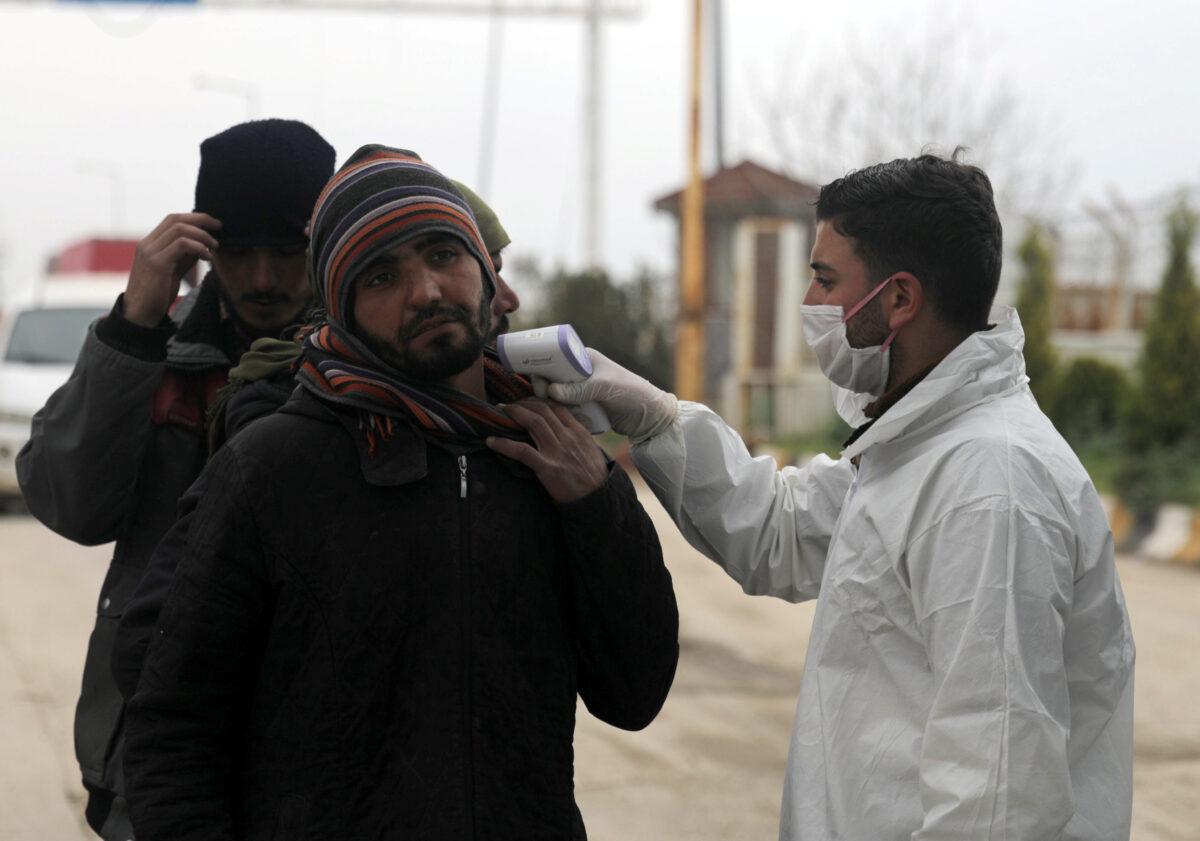 A health worker tests a man as part of security measures to avoid the spread of coronavirus, at the Bab el-Salam border crossing between the Syrian town of Azaz and the Turkish town of Kilis, seen from Syria on March 14, 2020. (Khalil Ashawi/Reuters)
