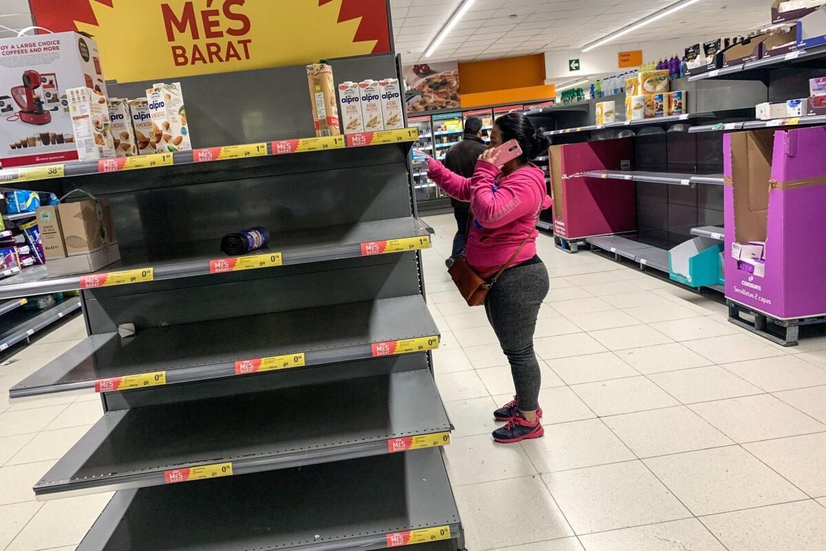 A woman speaks on her cellphone as stands next to empty shelves in Barcelona, Spain, on March 13, 2020. (David Ramos/Getty Images)