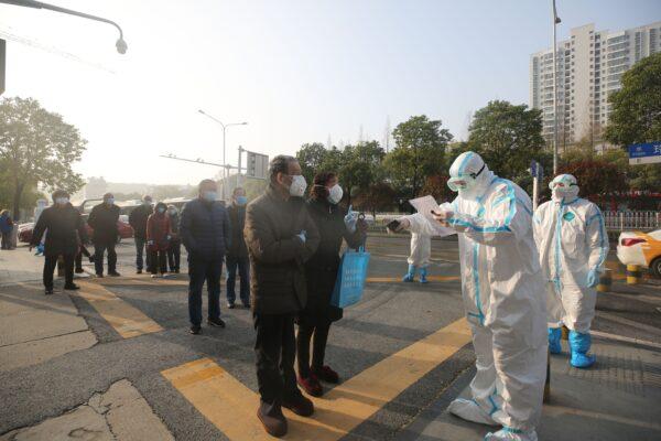 Medical workers (dressed in protective suits) check patients who recovered from COVID-19 as they arrive to be tested again at a hospital in Wuhan, Hubei Province, China, on March 14, 2020. (STR/AFP via Getty Images)