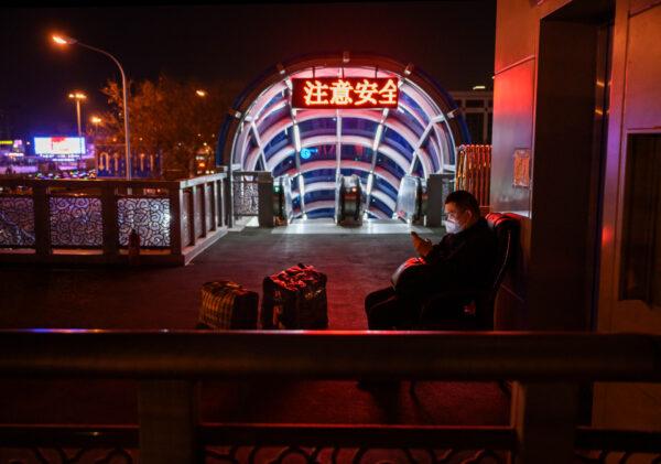 A Chinese man wears a protective mask as he sits outside Beijing station in Beijing, China, on March 13, 2020. (Kevin Frayer/Getty Images)