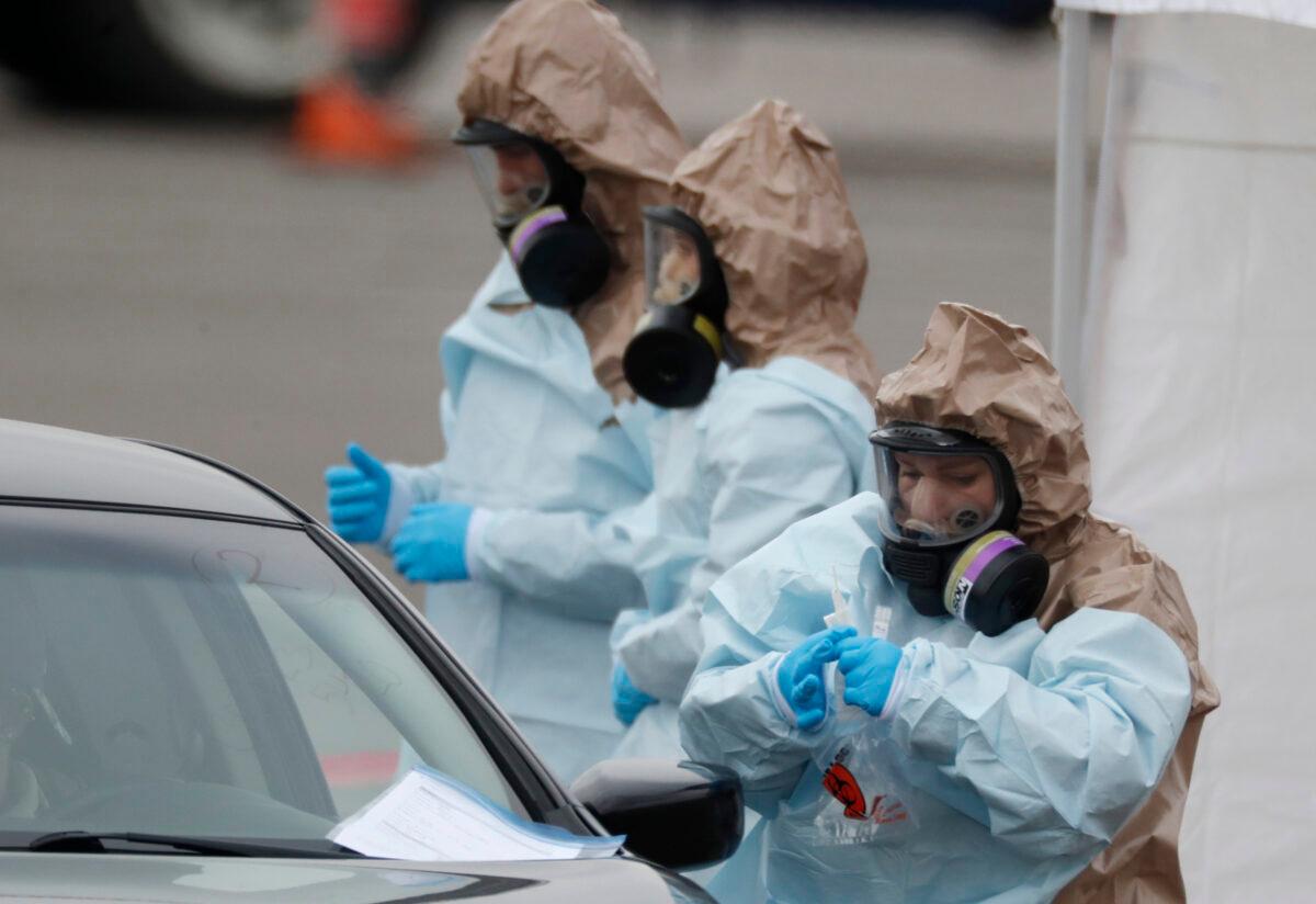 Colorado National Guard medical personnel perform coronavirus test on a motorist at a drive-through testing site outside the Denver Coliseum, in Denver, on, March 14, 2020. (David Zalubowski/AP Photo)