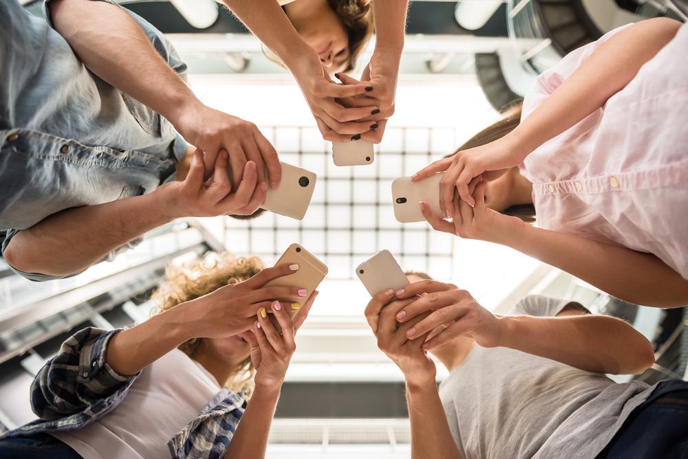 Illustration - Shutterstock | <a href="https://www.shutterstock.com/image-photo/group-students-standing-circle-using-phones-291227591">VGstockstudio</a>