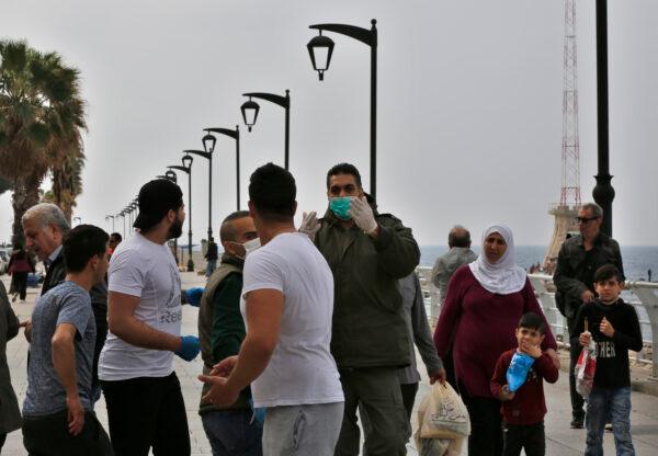 A municipal policeman (C) orders people to leave the waterfront promenade, along the Mediterranean Sea, as the country's top security council and the government were meeting over the spread of the new coronavirus, in Beirut, Lebanon, on March 15, 2020. (Hussein Malla/AP Photo)