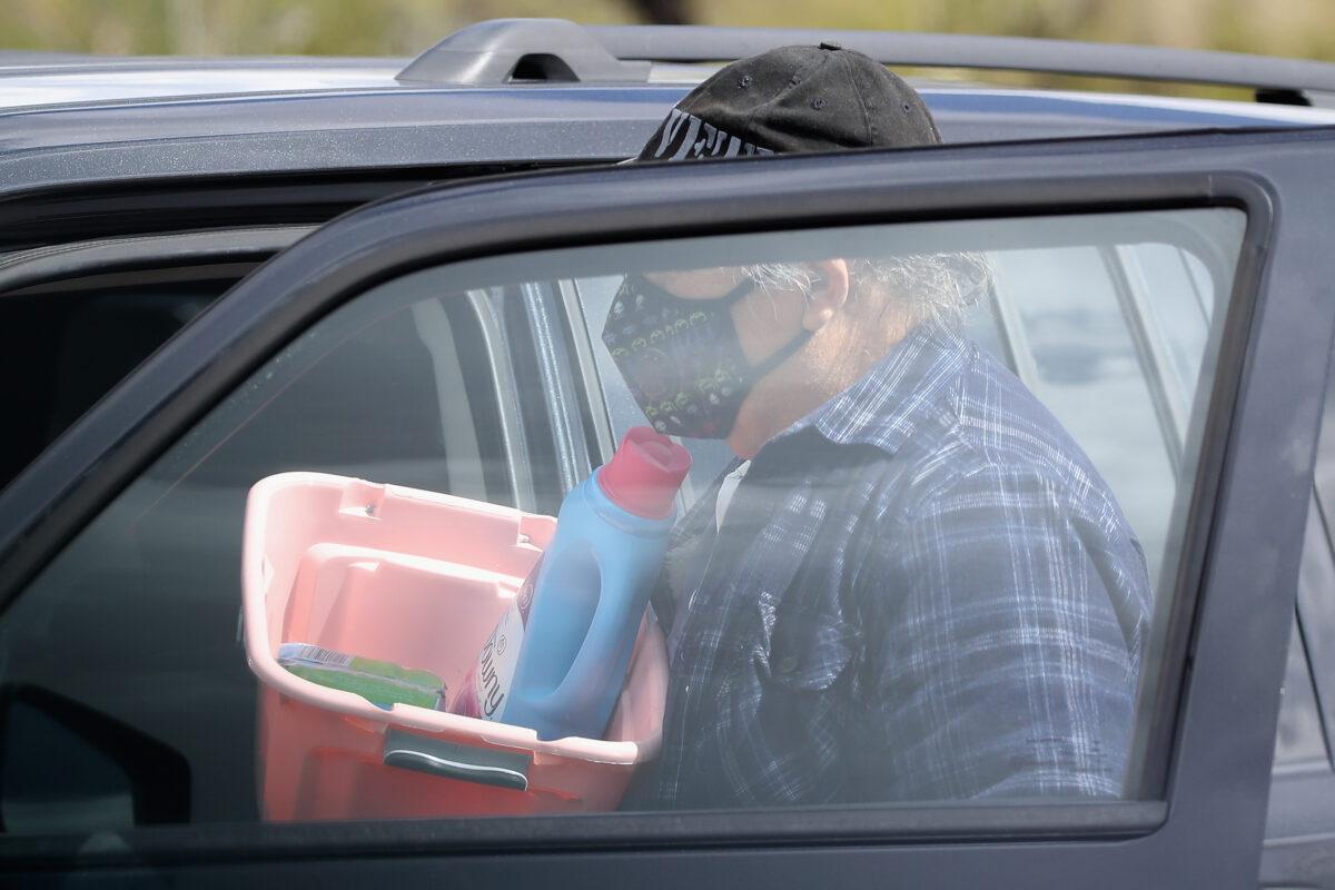 A man wearing a mask loads grocery items into his car at a Target store in Glendale, Arizona, on March 13, 2020. (Christian Petersen/Getty Images)