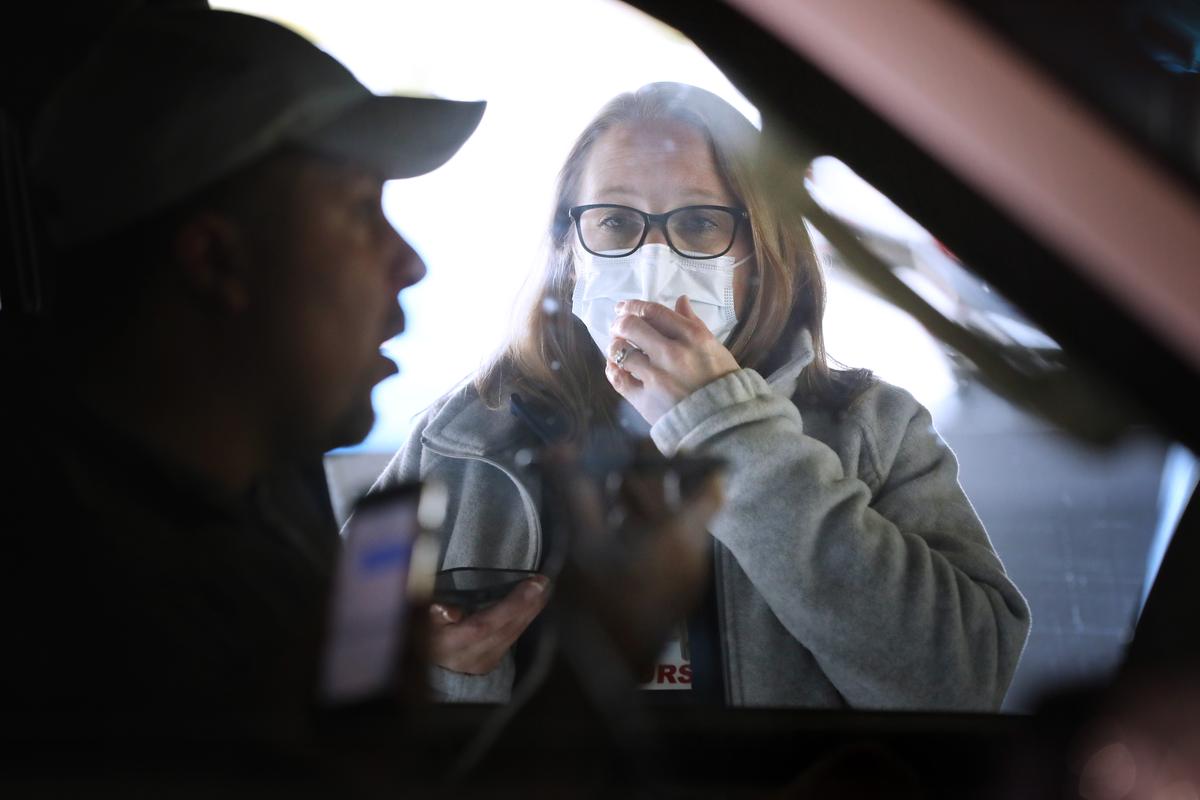Carroll Hospital Critical Care Unit Clinical Manager Stephanie Bakert talks to a person through his car window using a mobile phone before testing him for the coronavirus at a drive-thru station in the hospital's parking garage in Westminster, Maryland, on March 16, 2020. (Chip Somodevilla/Getty Images)